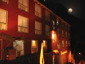 Um edifício com vários andares, janelas iluminadas e uma placa visível.