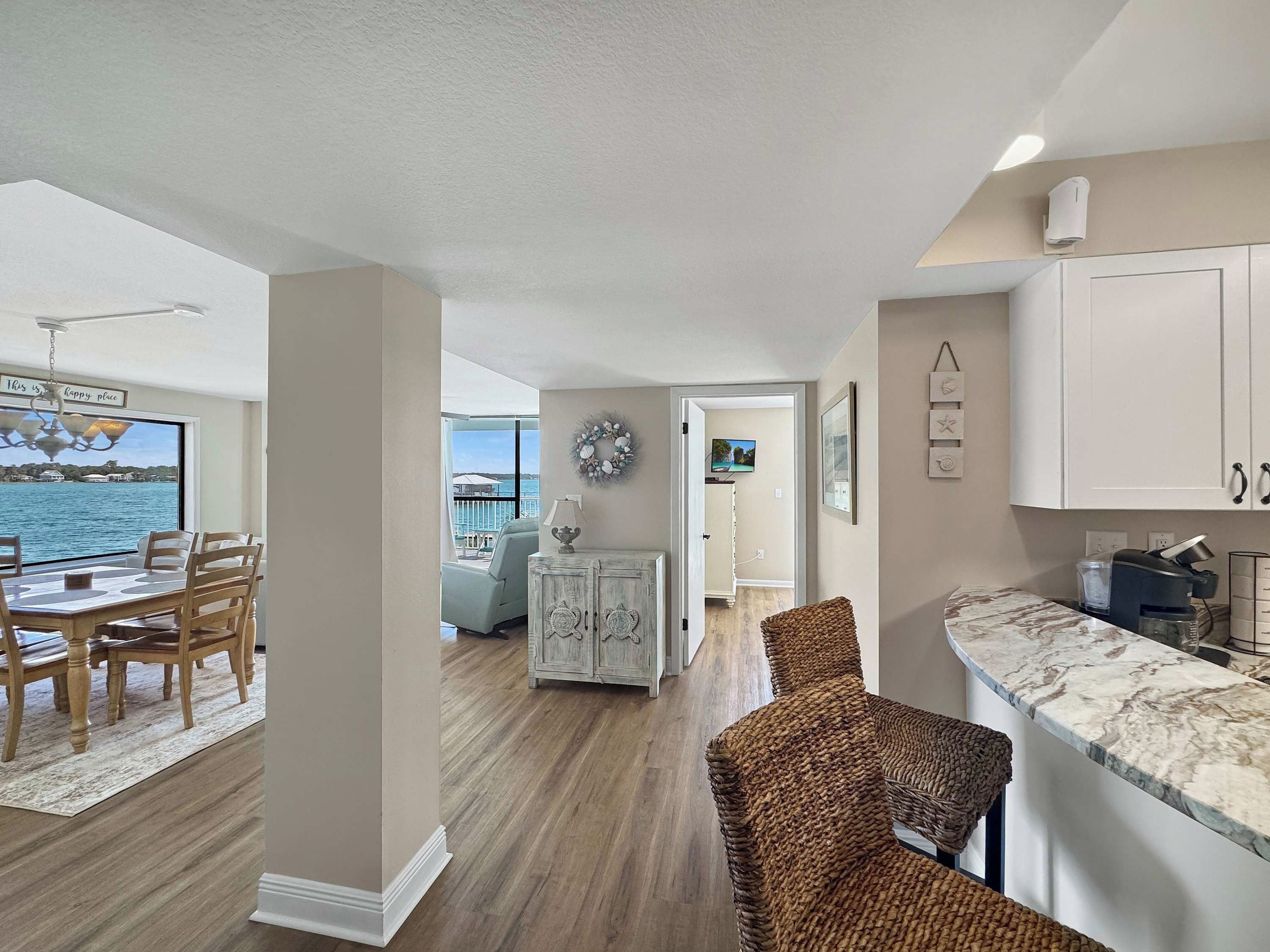 A spacious living area with a view of the water, a dining area with a table and chairs, and a kitchen with cabinets and a countertop.