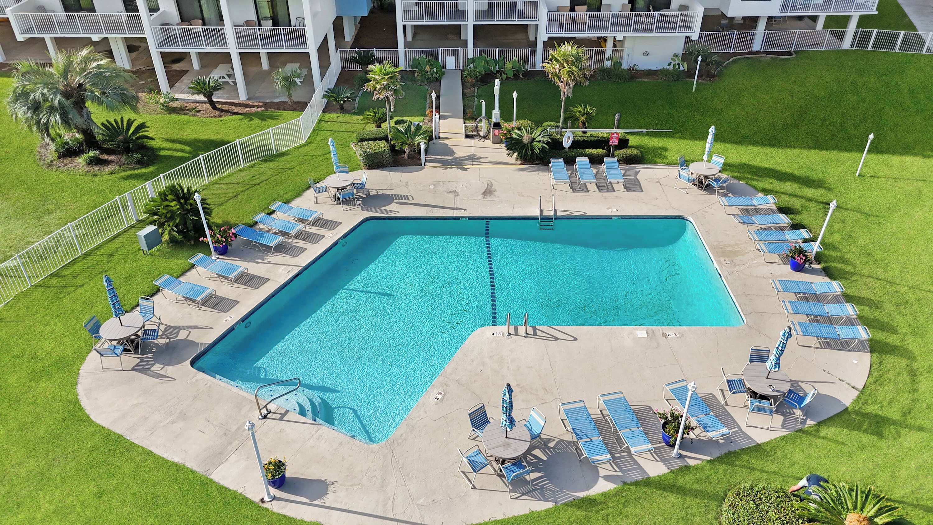 A swimming pool with lounge chairs and a small garden area.