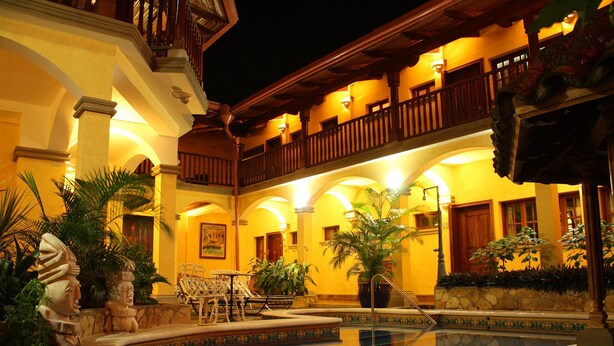 A pool area with a fountain, surrounded by outdoor seating and plants. - Colonial Granada Hotel (Granada)