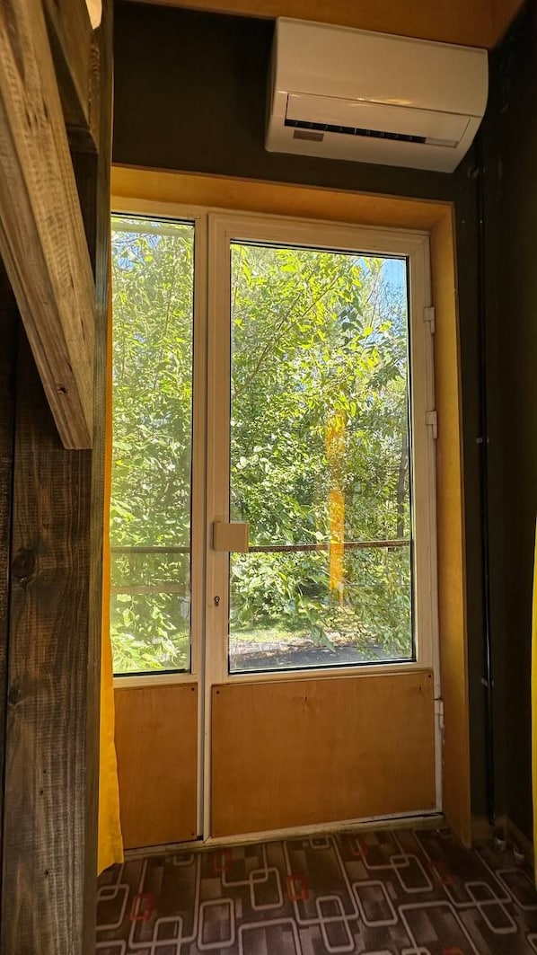 A room with a large window, a door, and an air conditioning unit.