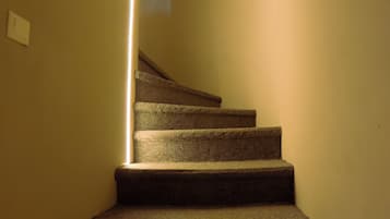 A carpeted staircase with a light fixture on the wall.