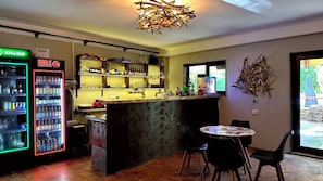 A bar area with a counter, stools, and a refrigerator stocked with beverages. - Camp & Hostel Maltakva (Poti)