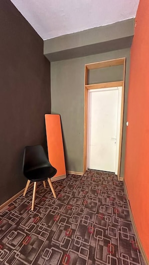 A narrow hallway with a patterned carpet, a black chair, and a white door.
