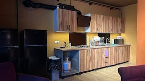 A compact kitchen with wooden cabinets, a gas stove, a microwave, and a refrigerator.