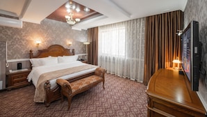 A hotel room with a large bed, a bench, a television, and a ceiling light. - Jannat Resort Koi-tash (Koy-Tash)