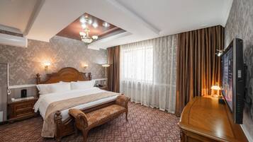 Habitación de hotel con una cama grande, un banco, un televisor y una lámpara en el techo.