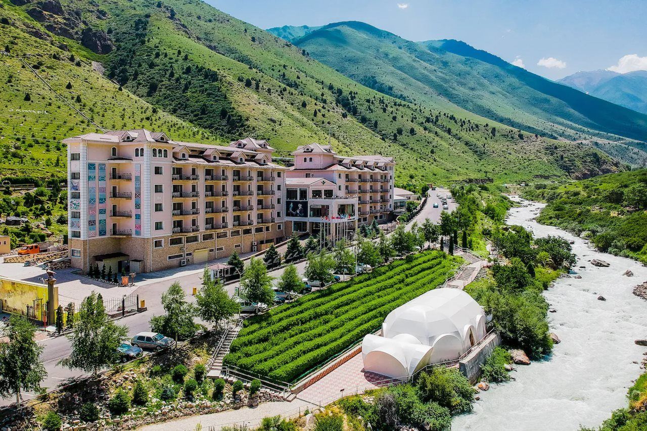 Un hotel de varios pisos, un patio central y un río que corre a su lado.