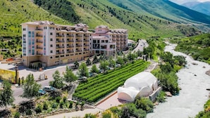 A hotel with multiple floors, a central courtyard, and a river nearby. - Jannat Resort Koi-tash (Koy-Tash)