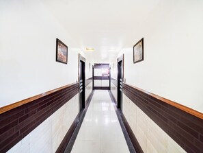 Un largo pasillo recto con piso y paredes de azulejos, con puertas a ambos lados.