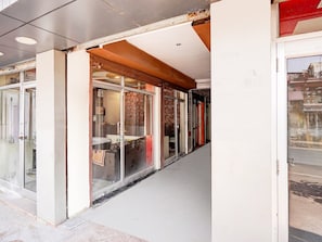 A corridor with glass doors leading to a room with a bed and a chair. - Classic Hotel Gupta Palace (Ajmer)