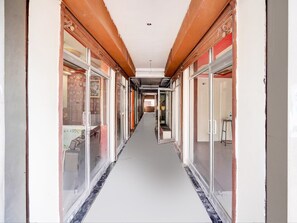 A corridor with glass doors and windows, leading to rooms with visible furniture. - Classic Hotel Gupta Palace (Ajmer)