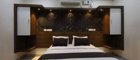 A modern bedroom with a bed, built-in wardrobe, and an air conditioning unit.