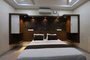 A modern bedroom with a bed, built-in wardrobe, and an air conditioning unit. - Deluxe Vishwa's Residency (Chennai)