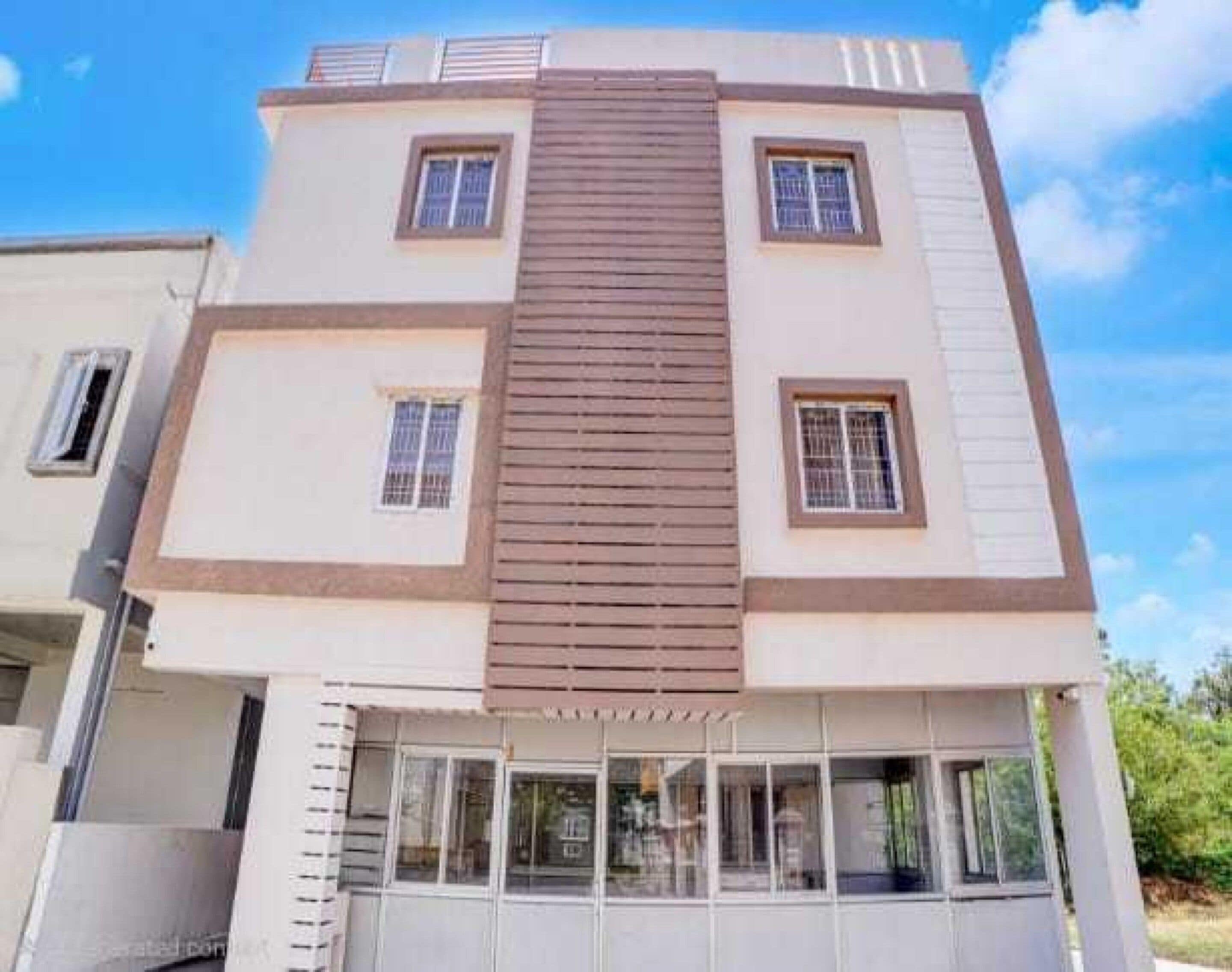Un edificio de varios pisos con fachada marrón central, múltiples ventanas y techo plano.