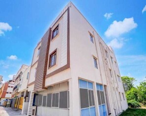 A modern multi-story residential building with a flat roof, large windows, and a visible garage entrance. - Deluxe Vishwa's Residency (Chennai)