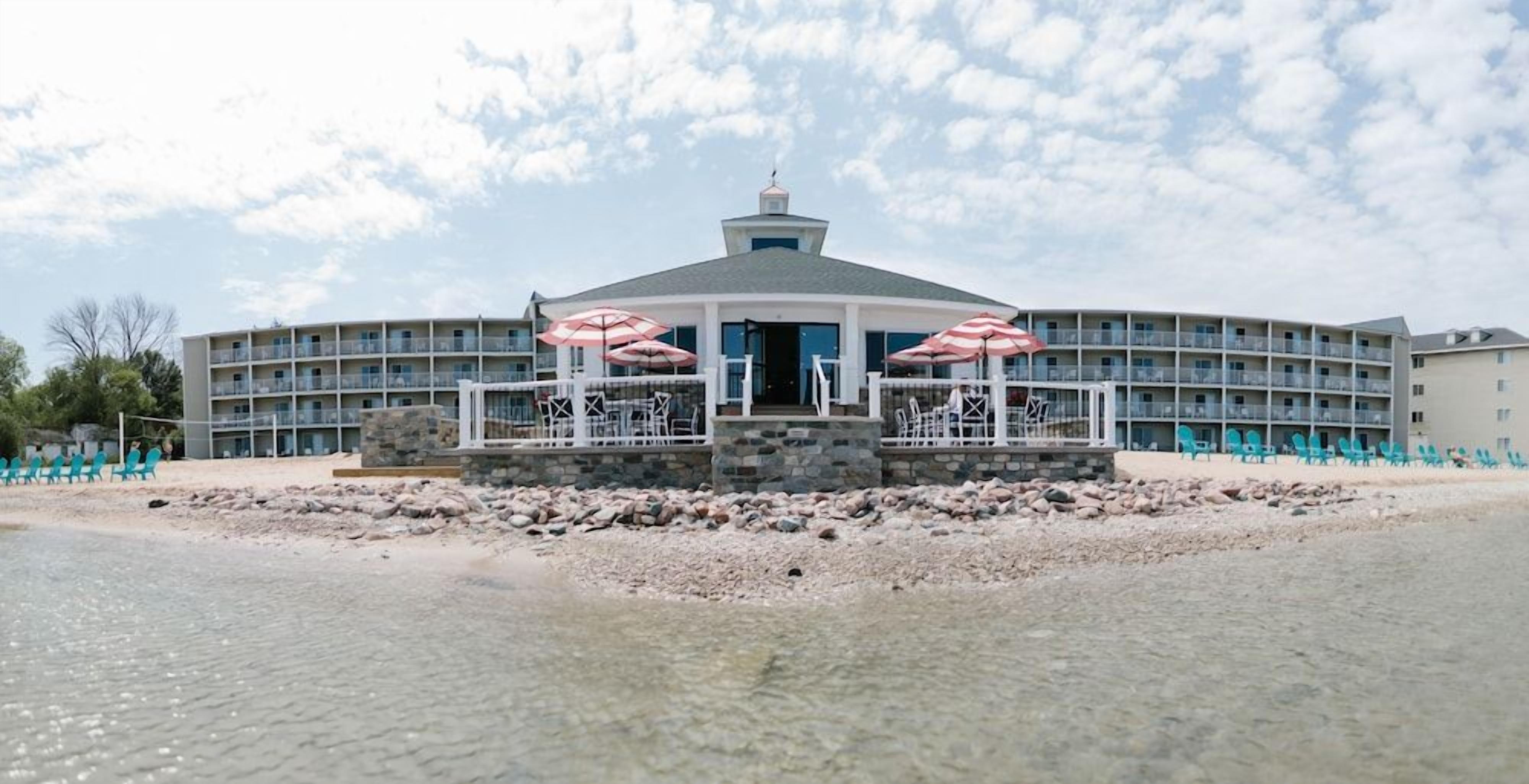A hotel with a central building, multiple balconies, and outdoor seating with umbrellas.
