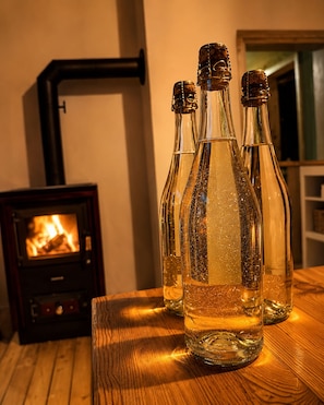 A wooden table with four glass bottles, a fireplace, and a wall-mounted heater.