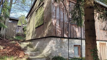 A rustic wooden building with a stone foundation, a small window, and a door.
