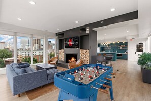 A modern living room with a foosball table, a fireplace, and a large TV screen displaying the Netflix logo. - 1Bd Condo in Downtown Minneapolis | Minutes from Convention Center and Stadium (Minneapolis)