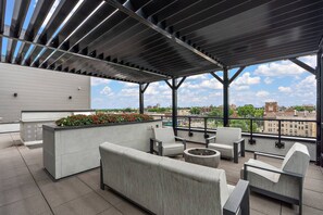 An outdoor seating area with a fire pit, a planter with flowers, and a view of the cityscape. - 1Bd Condo in Downtown Minneapolis | Minutes from Convention Center and Stadium (Minneapolis)
