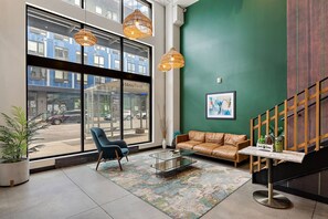 A lobby with a sofa, chair, glass coffee table, and a view of the street outside. - 1Bd Condo in Downtown Minneapolis | Minutes from Convention Center and Stadium (Minneapolis)