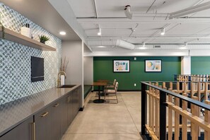 Une cuisine moderne avec un mur recouvert de carreaux décoratifs, un coin repas comprenant une table et des chaises, et un mur d’accent vert agrémenté d’œuvres d’art.