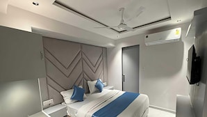 Une chambre à coucher moderne, équipée d’un lit, de tables de chevet, d’un ventilateur de plafond et d’un appareil de climatisation.