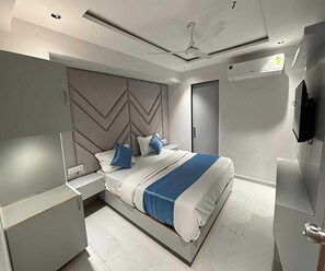 Un dormitorio moderno con cama, mesitas de noche, ventilador de techo y aire acondicionado.