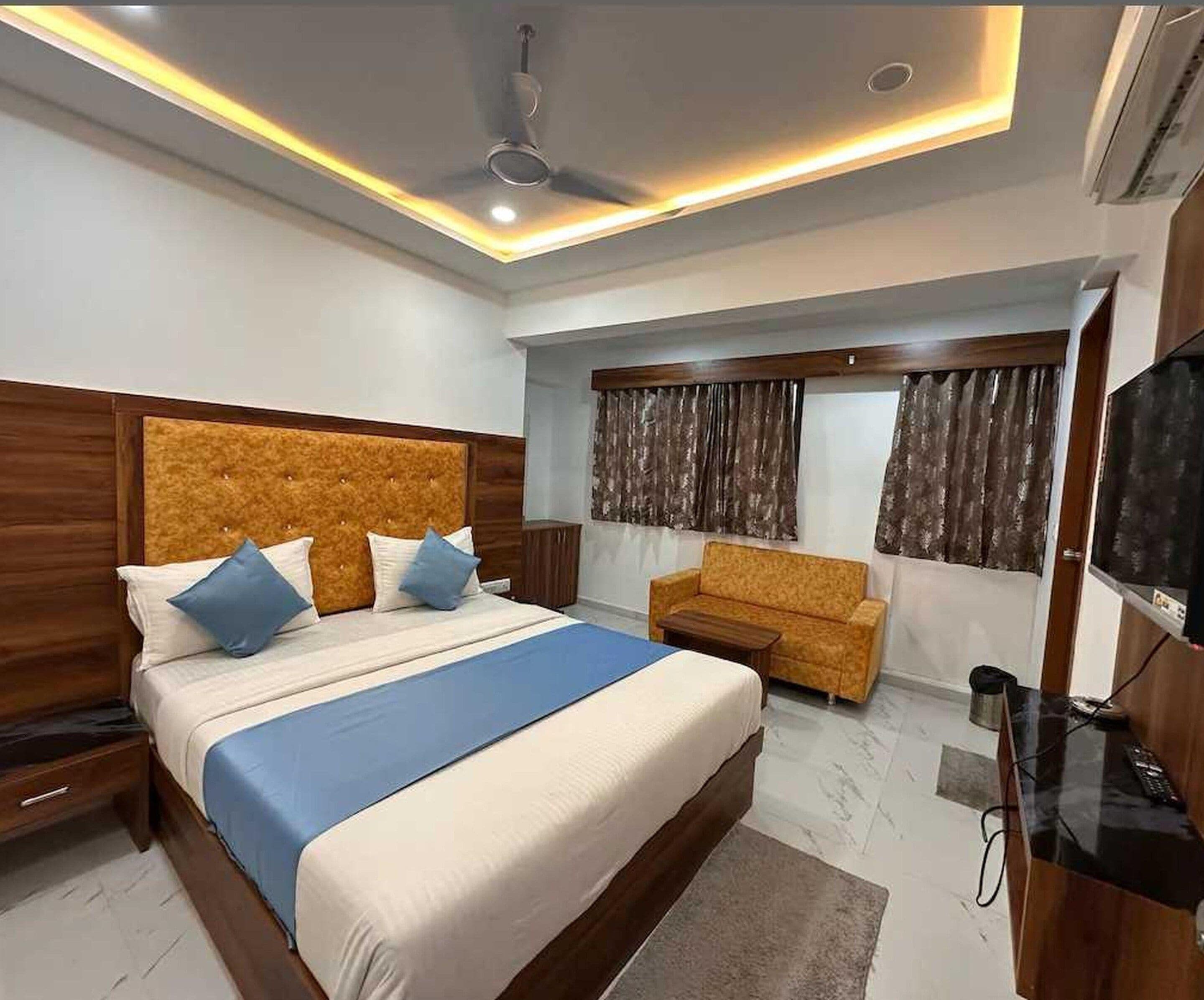 Un dormitorio moderno con una cama grande, un sofá, un televisor y un ventilador de techo.
