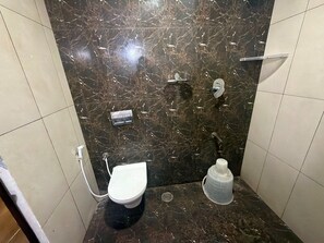 A bathroom with a toilet, a shower, and a sink. - Deluxe With Balcony Hotel Prime Bliss (Bengaluru)