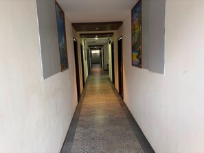A long, narrow hallway with patterned flooring and doors on both sides. - Deluxe With Balcony Hotel Prime Bliss (Bengaluru)