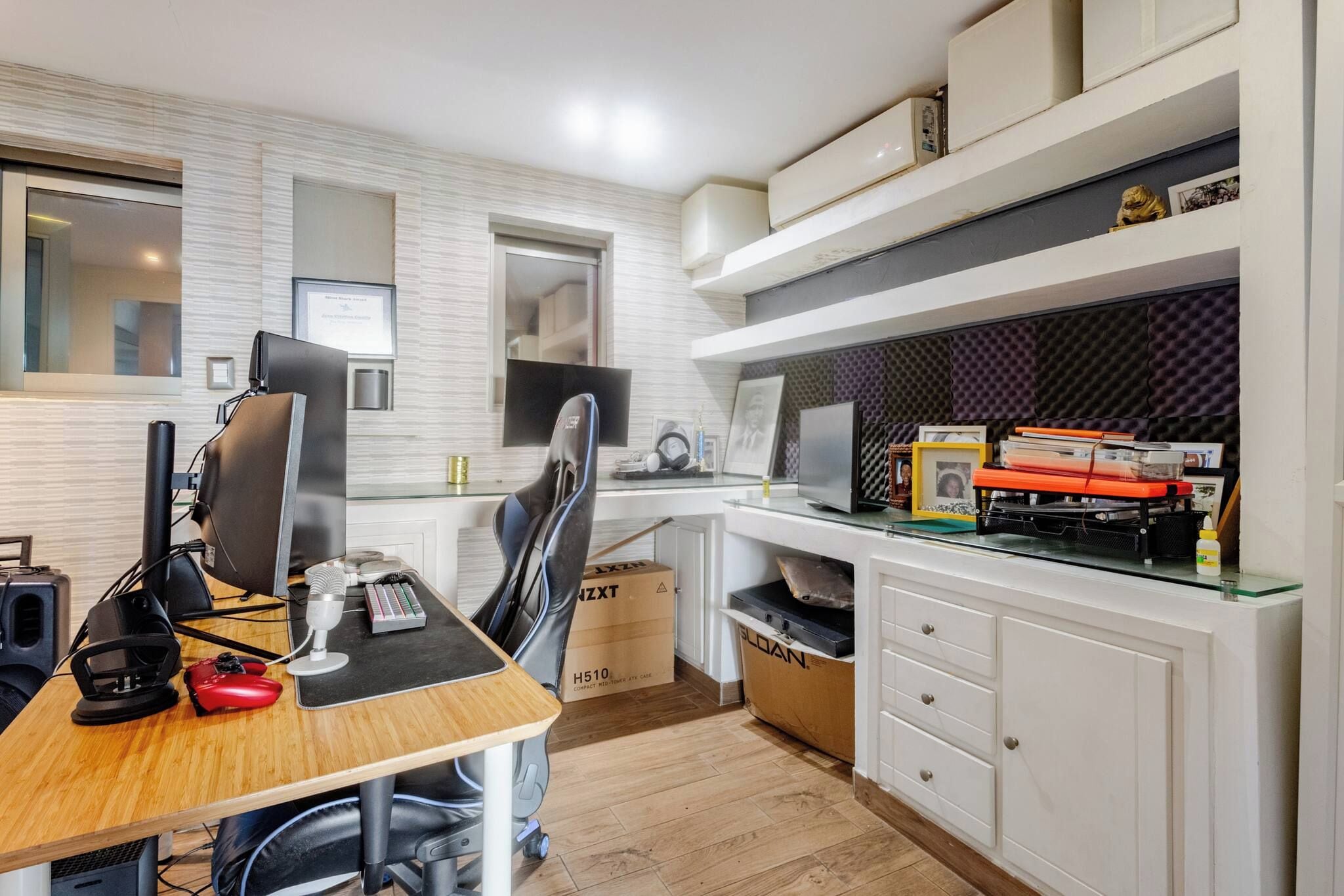 A modern kitchen with a dining area, equipped with a computer, gaming console, and various kitchen appliances.