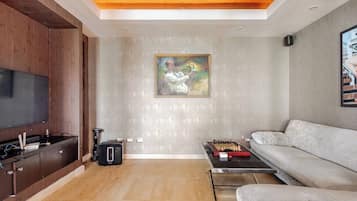 A modern living room with a flat-screen TV, a coffee table with a chess set, a sofa, and a painting on the wall.