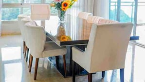 A modern dining area with a glass table, white chairs, and a vase of flowers. - Apartamento de Lujo Frente al Mar con Jacuzzi (Santo Domingo)