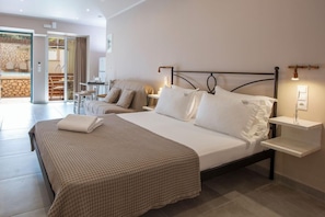 Habitación de hotel con cama, mesitas de noche, lámpara y vista a un espacio exterior.