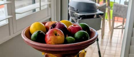 Un balcón con una mesa que sostiene un bol de fruta y una parrilla.