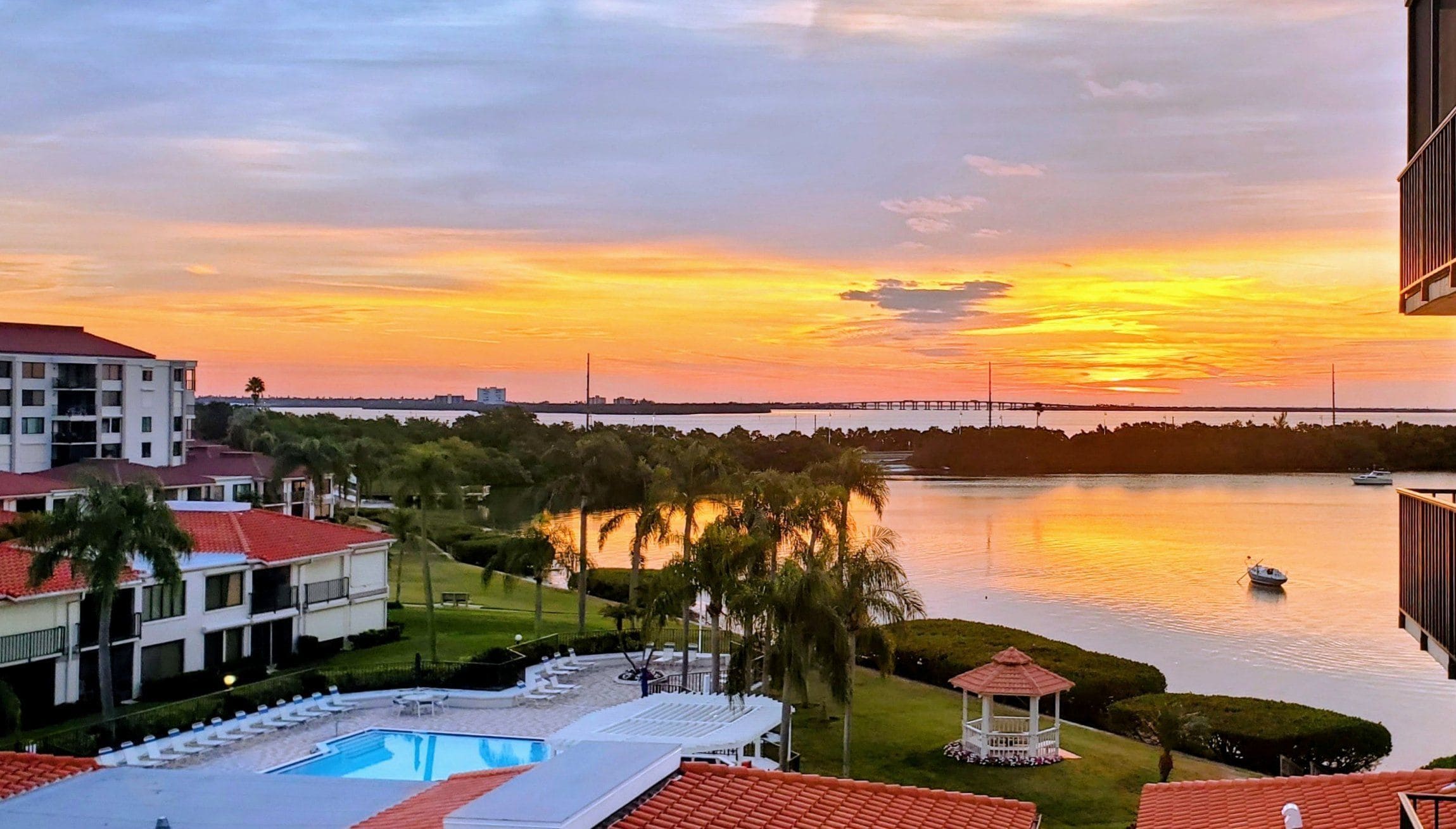 Un complexe hôtelier doté d’une piscine, d’un belvédère et offrant une vue sur le coucher de soleil au-dessus d’une étendue d’eau.