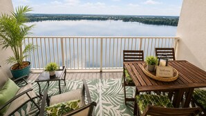 A balcony with a view of a lake, a wooden table with a 'Welcome' sign, and outdoor seating. - Tranquil 1-bedroom apartment in vibrant Orlando Sleep 7 (Orlando)