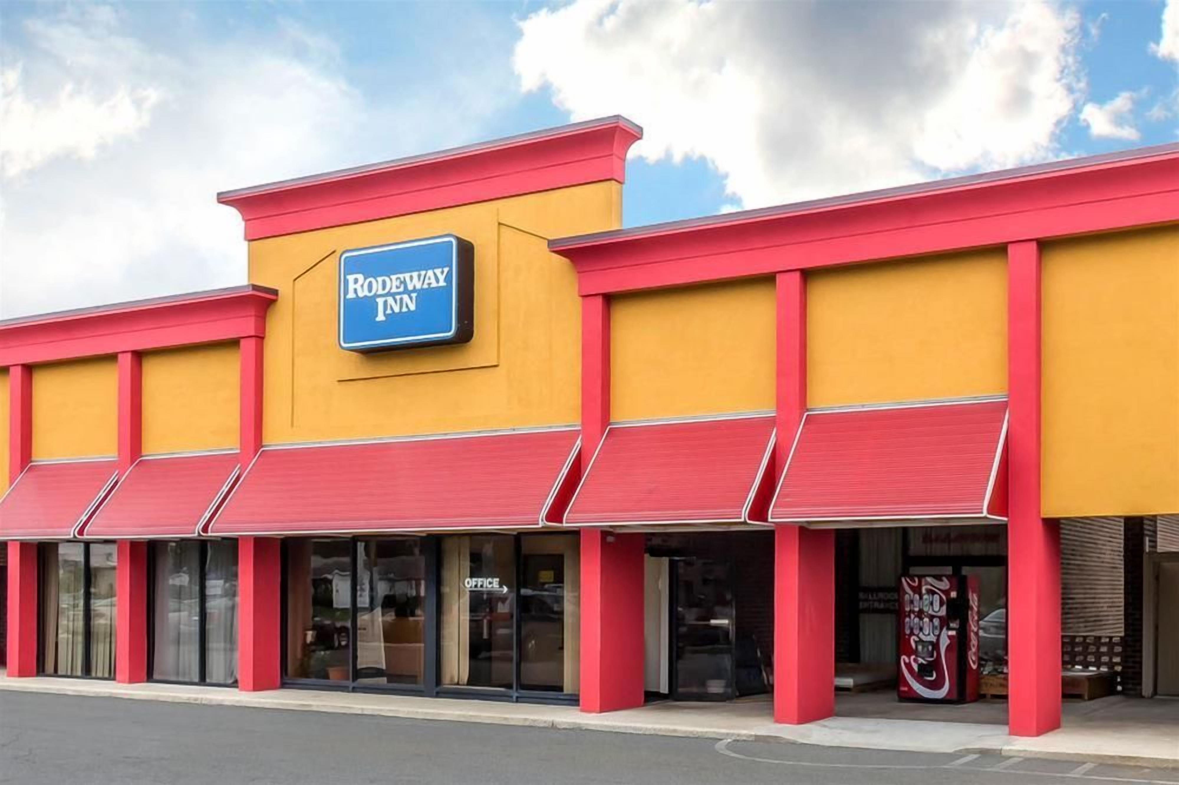 A Rodeway Inn with a yellow facade, red awnings, and a blue sign.