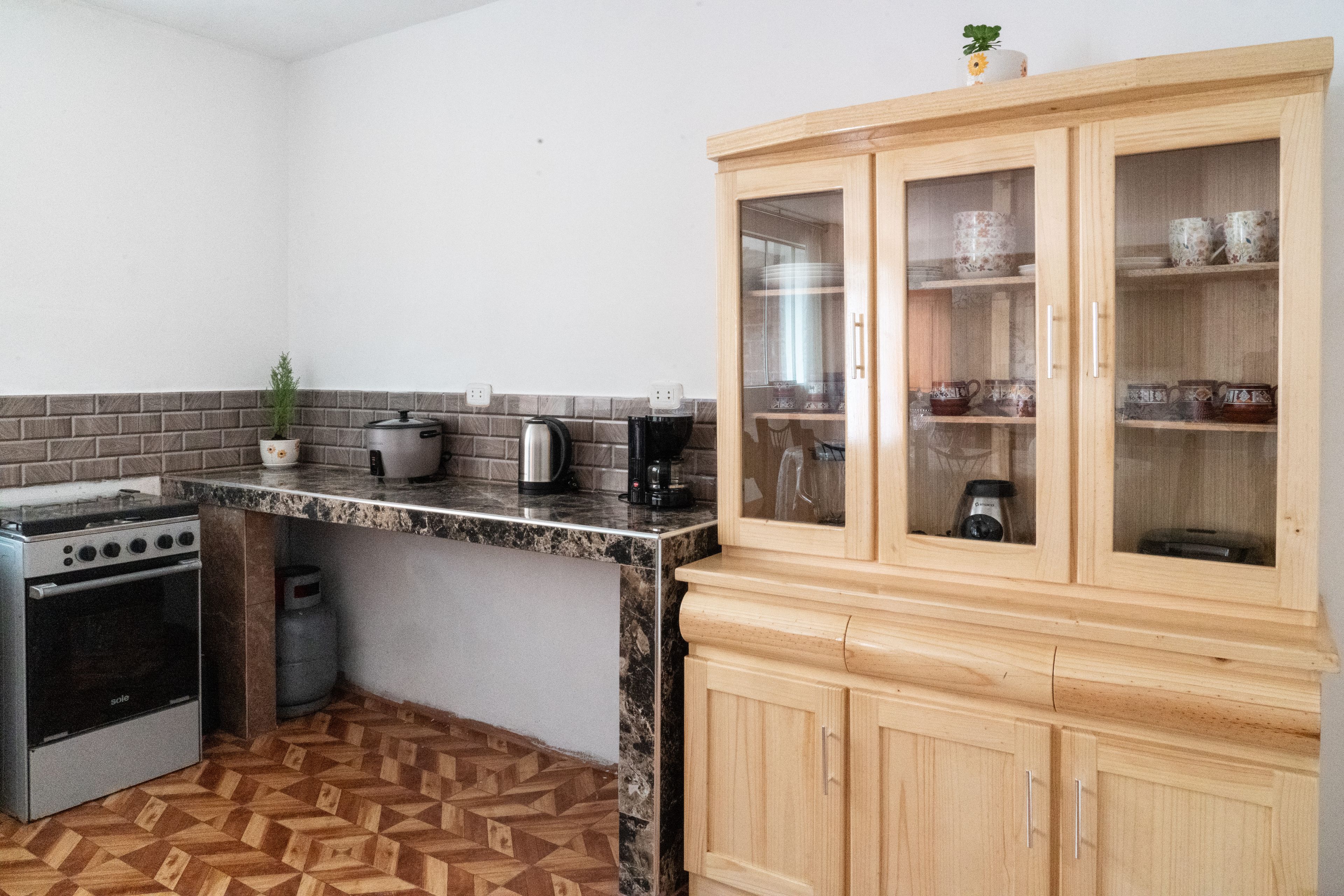 A compact kitchen with a stove, kettle, and coffee maker.