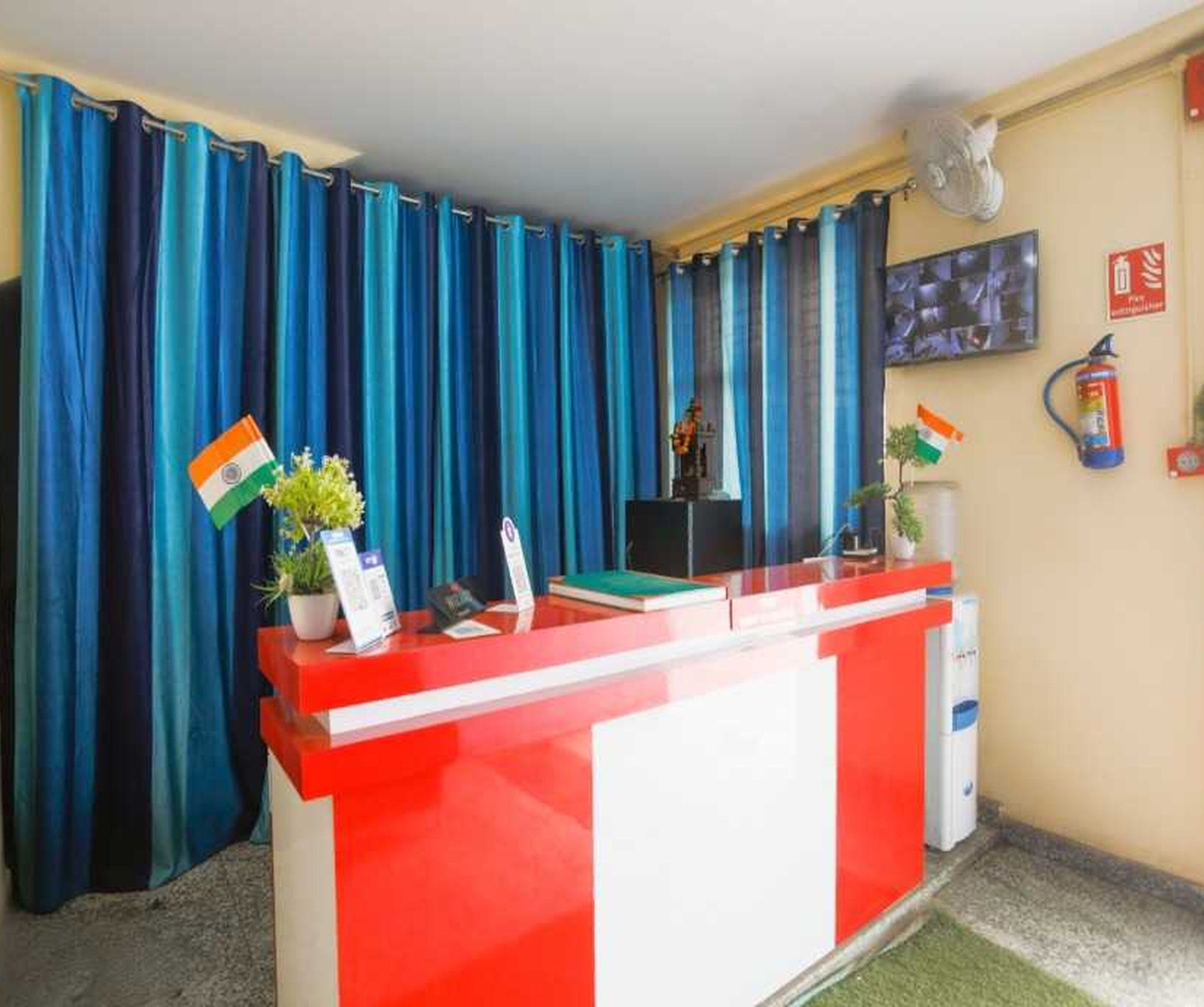 Un mostrador de recepción con una decoración en rojo y blanco, cortinas azules y una bandera en la pared.