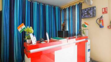 Un mostrador de recepción con una decoración en rojo y blanco, cortinas azules y una bandera en la pared.