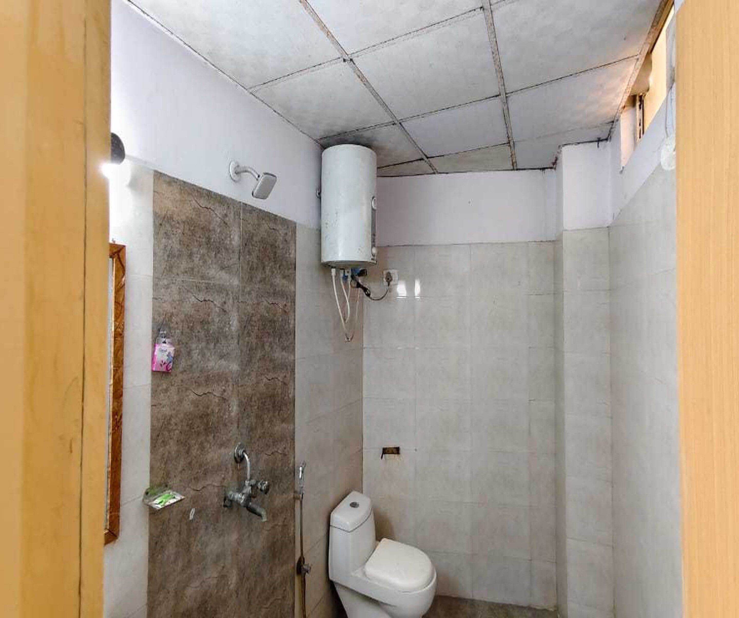 Un baño pequeño con ducha, inodoro y calentador de agua.