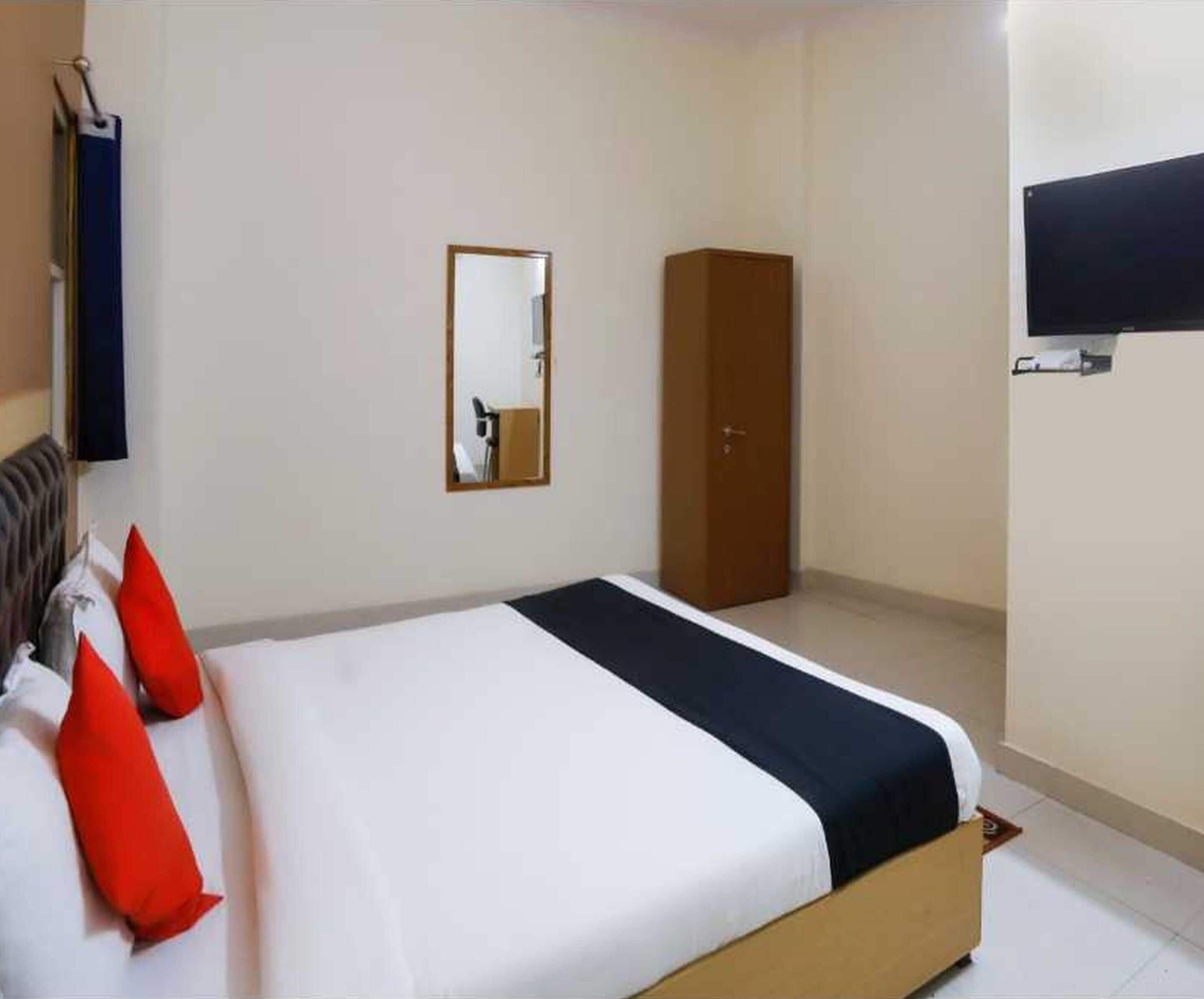 A hotel room with a bed, a wardrobe, a mirror, and a television.