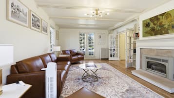 A spacious living room with a brown leather sofa, a coffee table, and a fireplace.