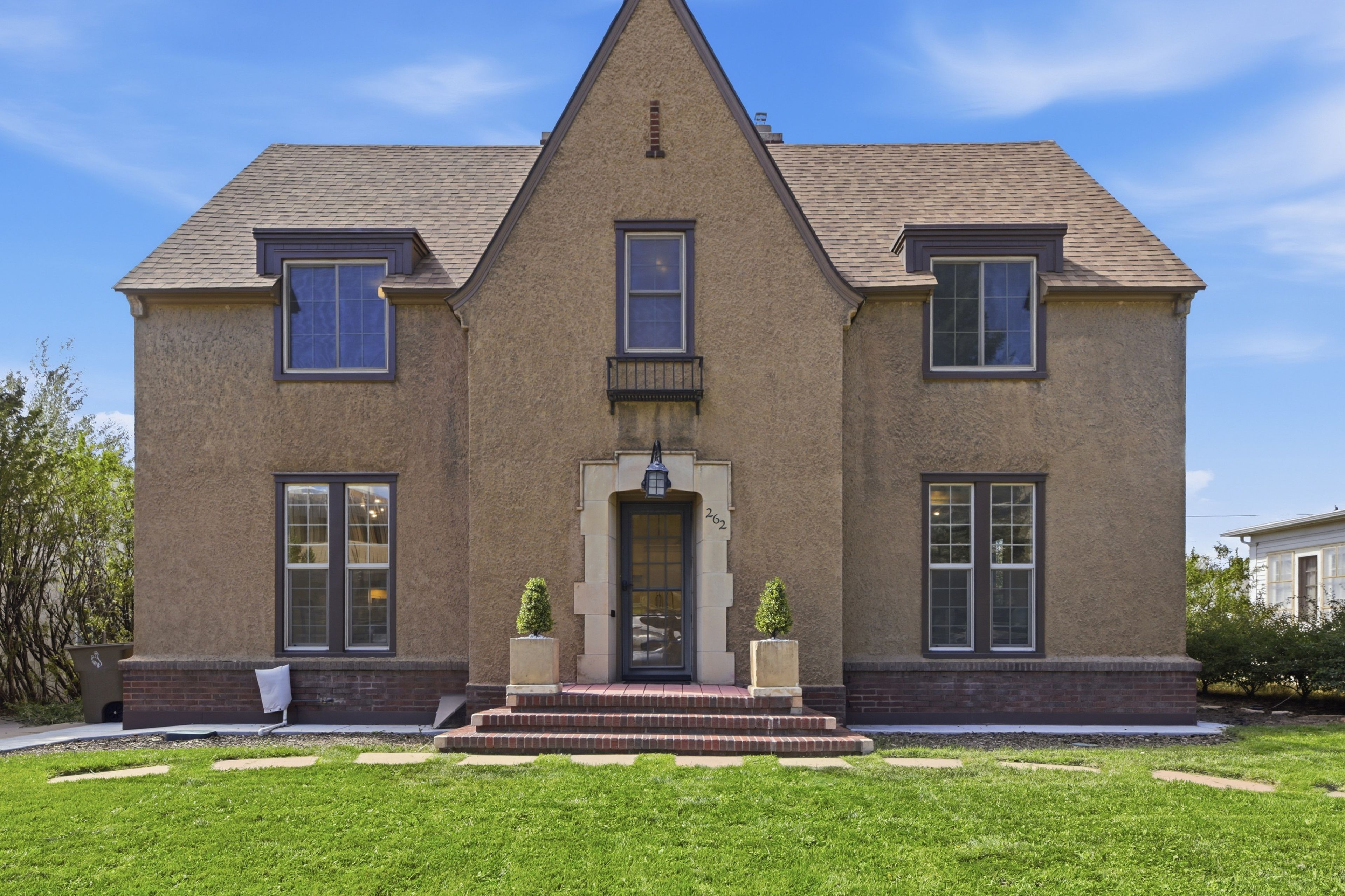 A two-story building with a symmetrical facade, a central entrance with steps, and a small porch area.