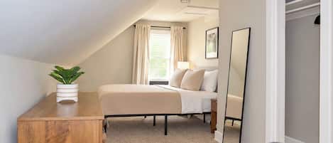 Quarto com cama, mesa de cabeceira e planta em vaso.