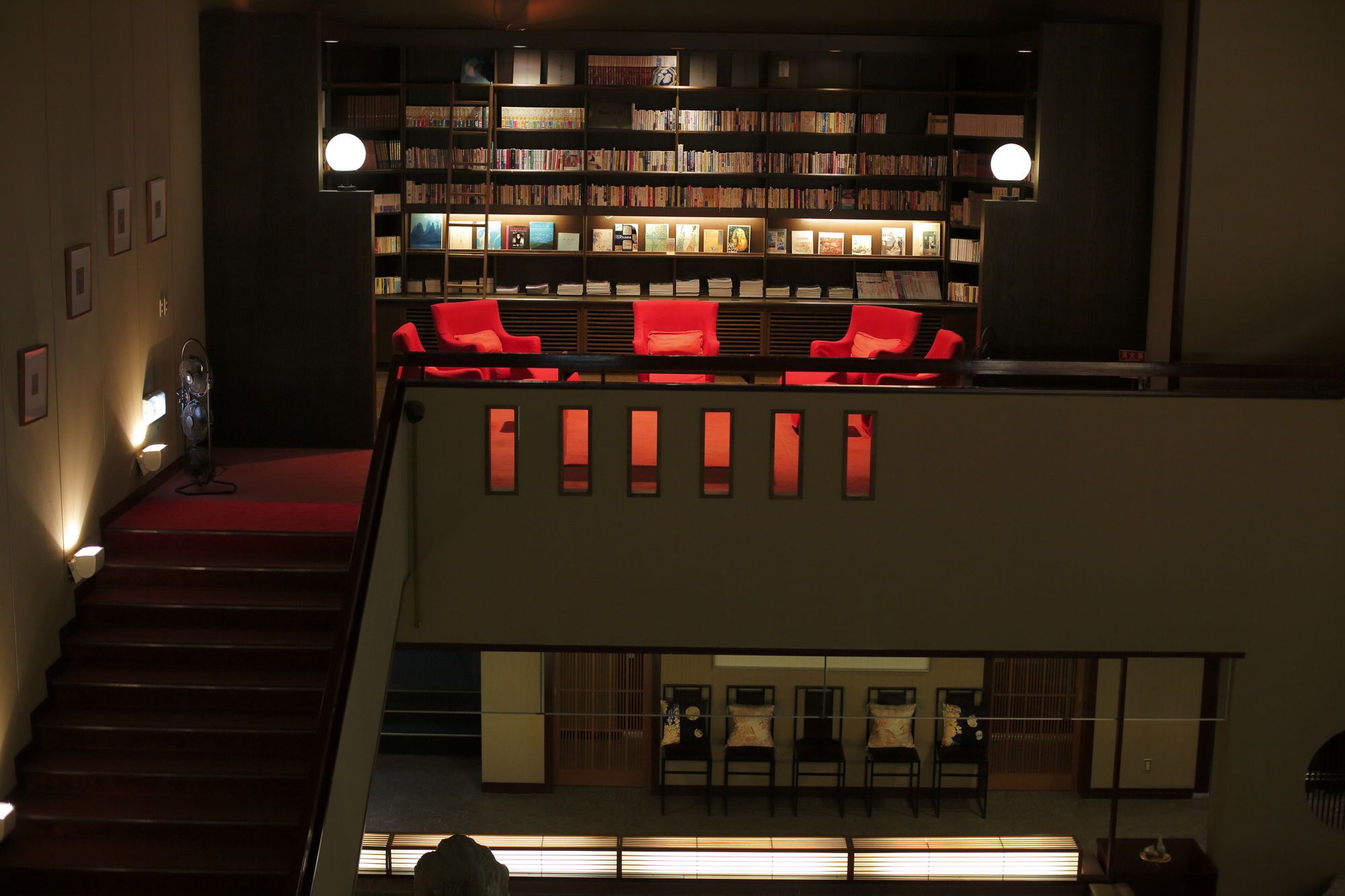 Una biblioteca con estanterías, sillas rojas y una escalera.