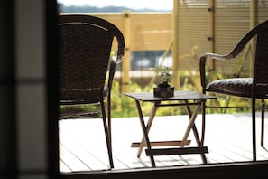 A wooden deck with two wicker chairs and a small table, one of which has a potted plant. - Yamashiro Onsen Onsen Meisoclub Fujiya (Kaga)